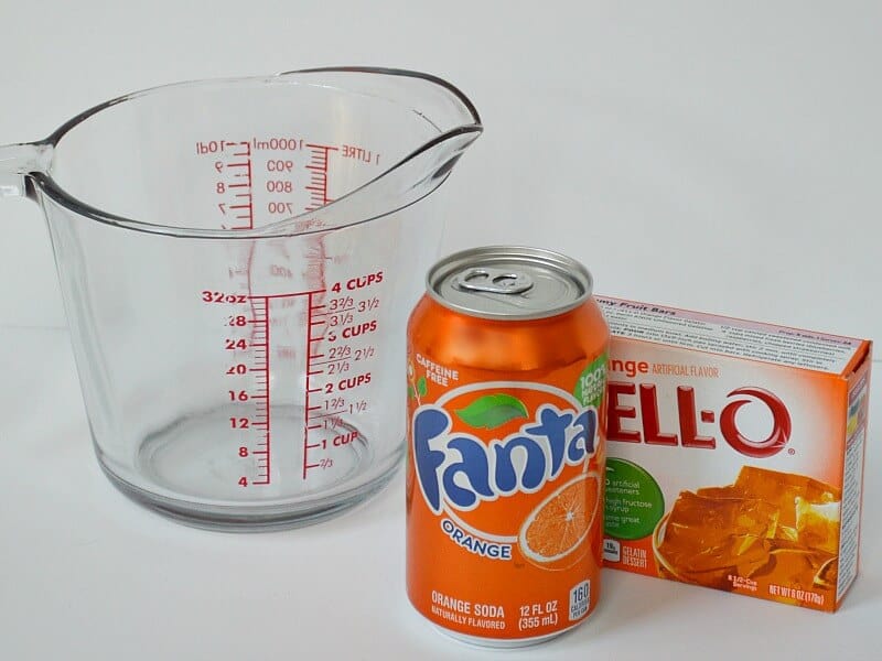 can of orange soda and box of orange gelatin next to clear measuring cup.