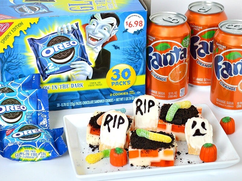 graveyard dessert next to cans of orange soda and blue box of Halloween Oreos.