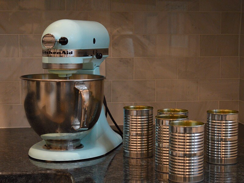 5 tin cans next to blue mixer with bowl