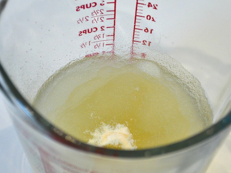 overhead view of gelatin powder and liquid in clear measuring cup.