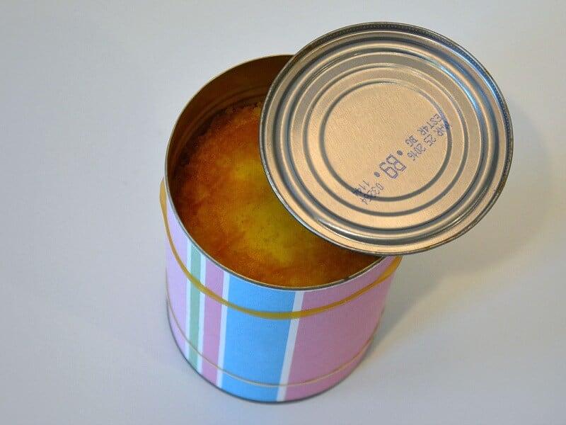 decorated tin can with cupcake inside and lid on side of can