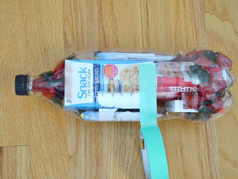 overhead view of snacks in clear 2-liter soda bottle with green washi tape wrapped around cut middle of bottle