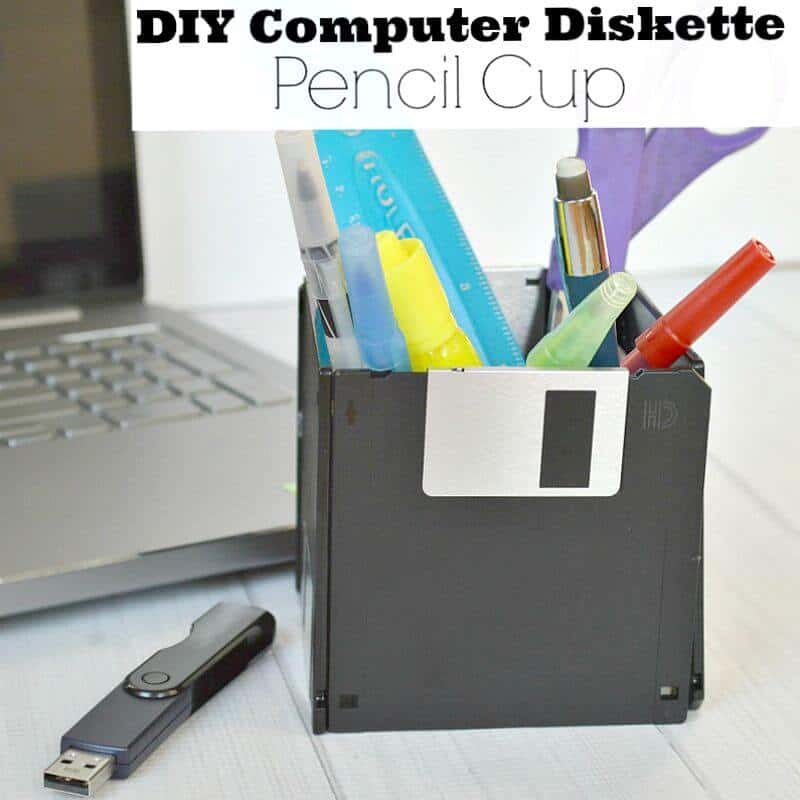 close up of diskette pen holder with flash drive next to laptop computer