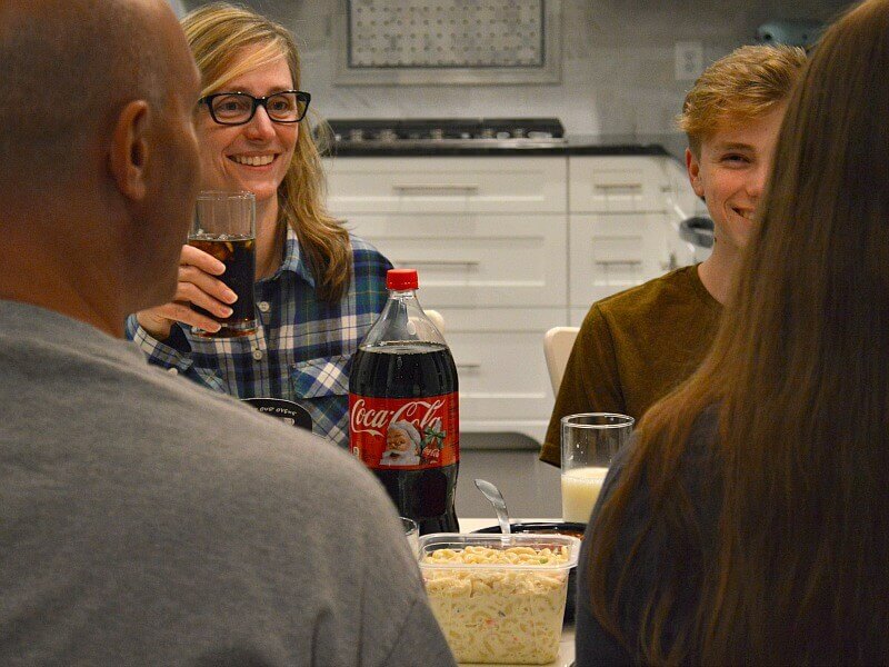 family of 4 at dinner table smiling and bottle of Coca-cola