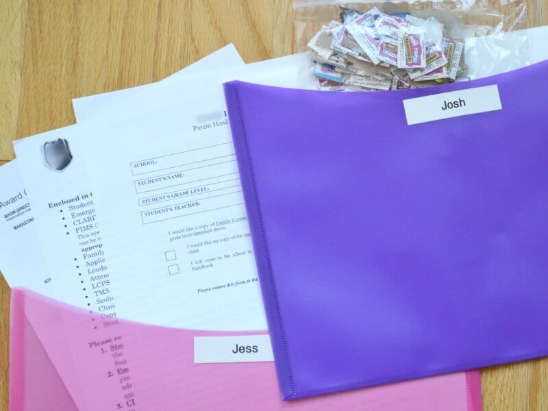 overhead view of pink folder and purple folder with names andhomework papers and bag of cut out box tops