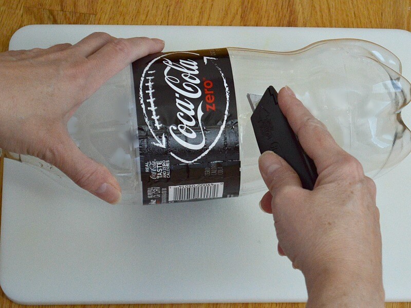 overhead view of hands holding empty soda bottle and cutting the middle 