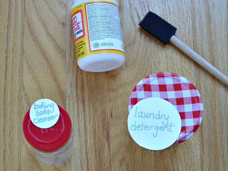 overhead view of bottle of with yellow label, sponge brush and 2 jars with round handwritten labels sitting slightly ajar on top 