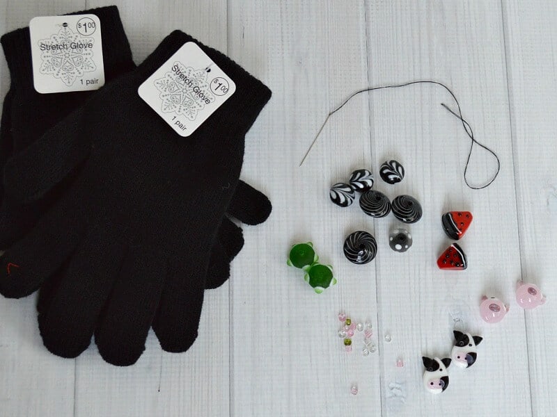 2 new pairs of black knit gloves with scattered beads on white wood table