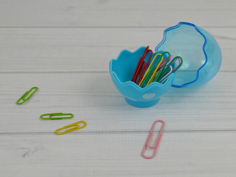 blue plastic egg holding colorful paper clips