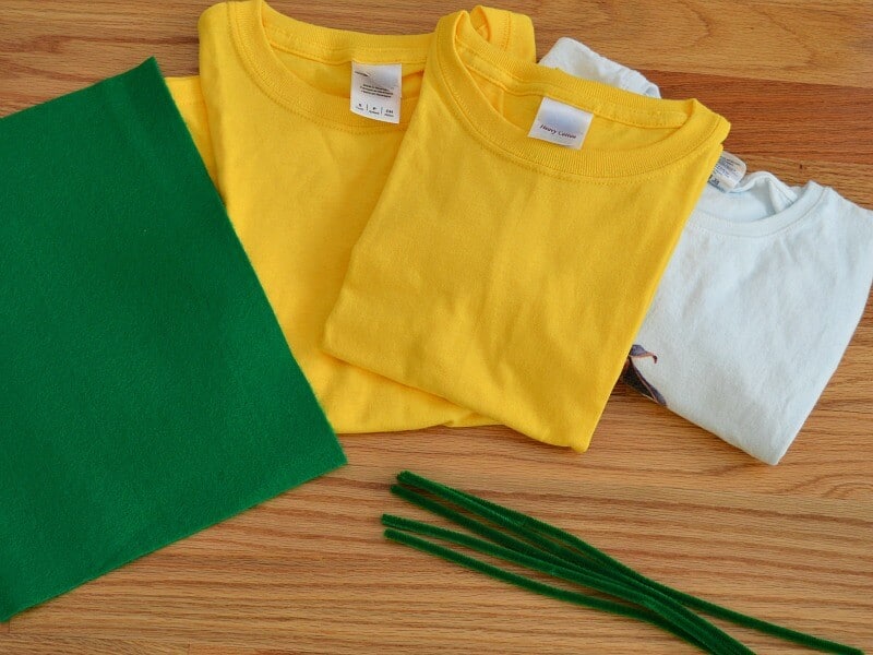 3 folded t-shirts, green felt and green  pipe cleaners on table