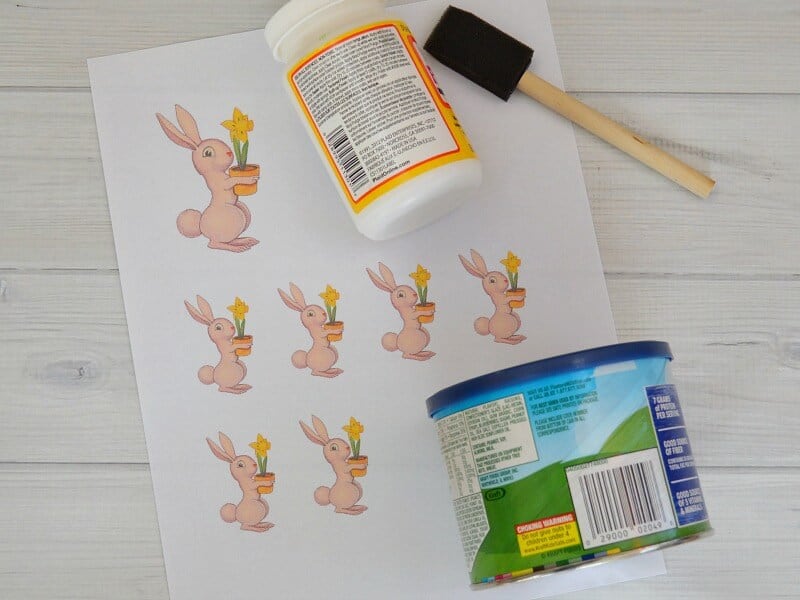 overhead view of bunny images on paper, can, bottle of glue and sponge brush