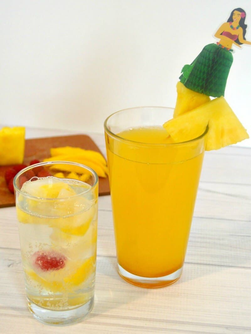 2 glasses with drinks and slice of pineapple on white wood table