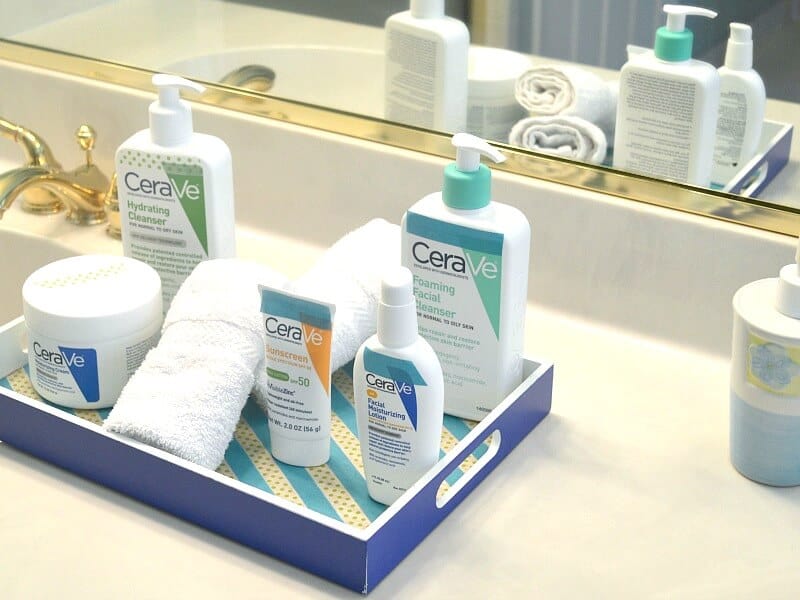 blue wood tray holding bottles of skin care on bathroom counter.