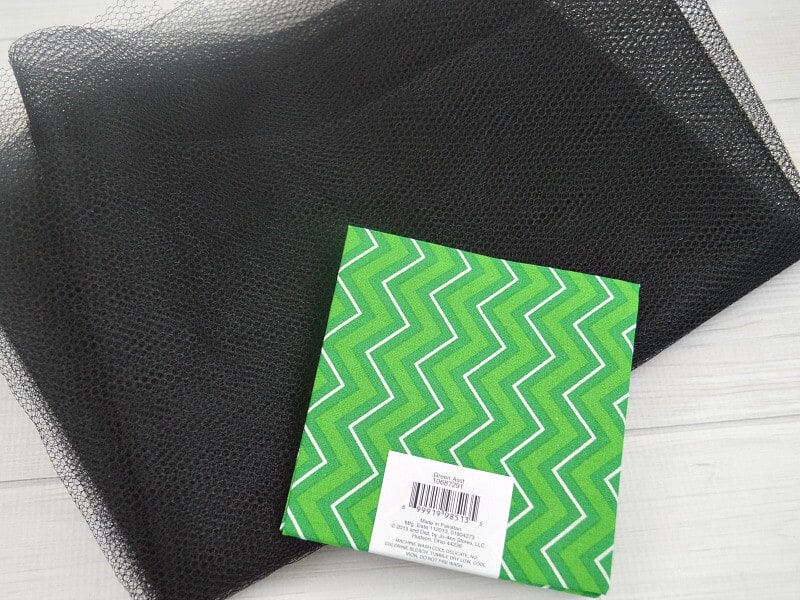 black mesh fabric and green fabric fat quarter on white table