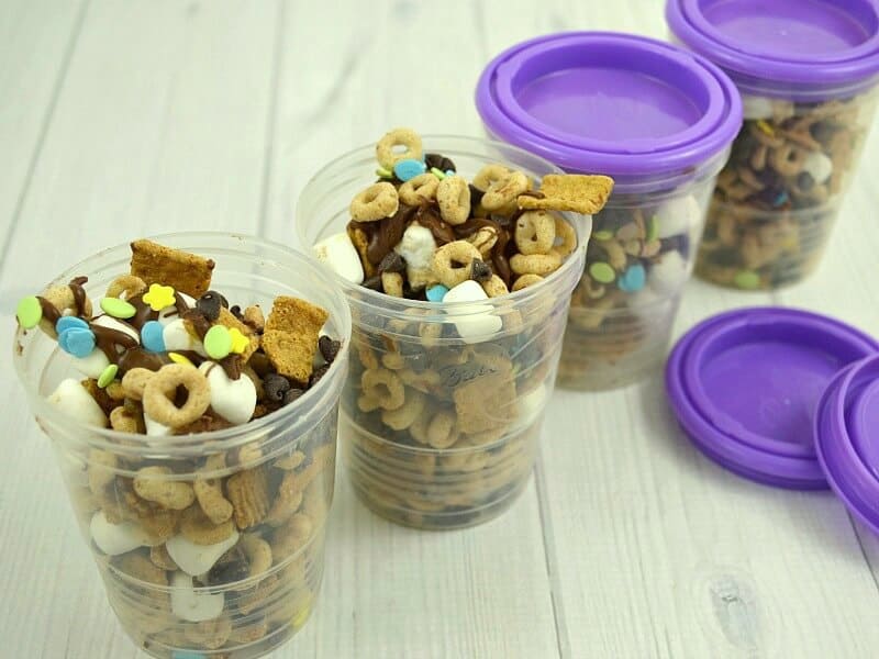 small plastic containers filled with cereal snack mix, 2 with lids and 2 with lids off