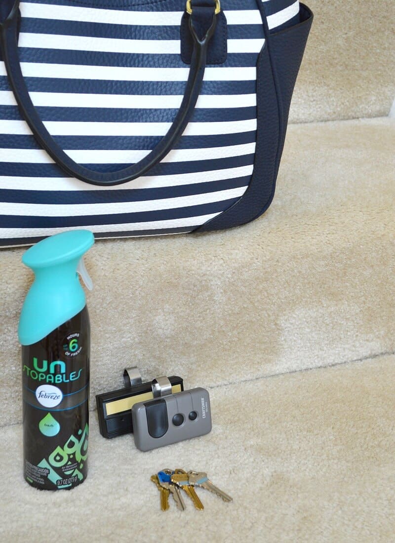 blue and white striped purse on stairs with 2 garage door openers, keys and bottle of air freshener