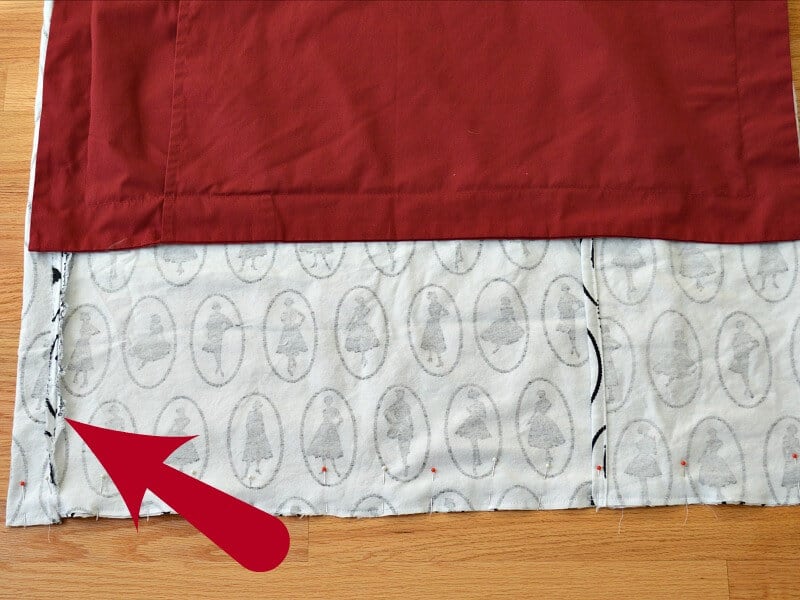 red pillow sham laying next to white and black fabric inside out with red arrow pointing to a seam