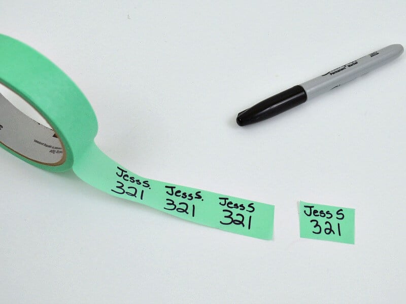 green roll of masking tape, black marker and name with number written on tape.