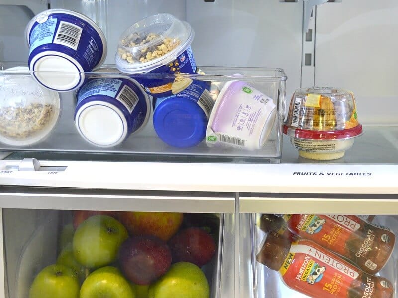 milk bottles, apples and yogurt containers in refriderator