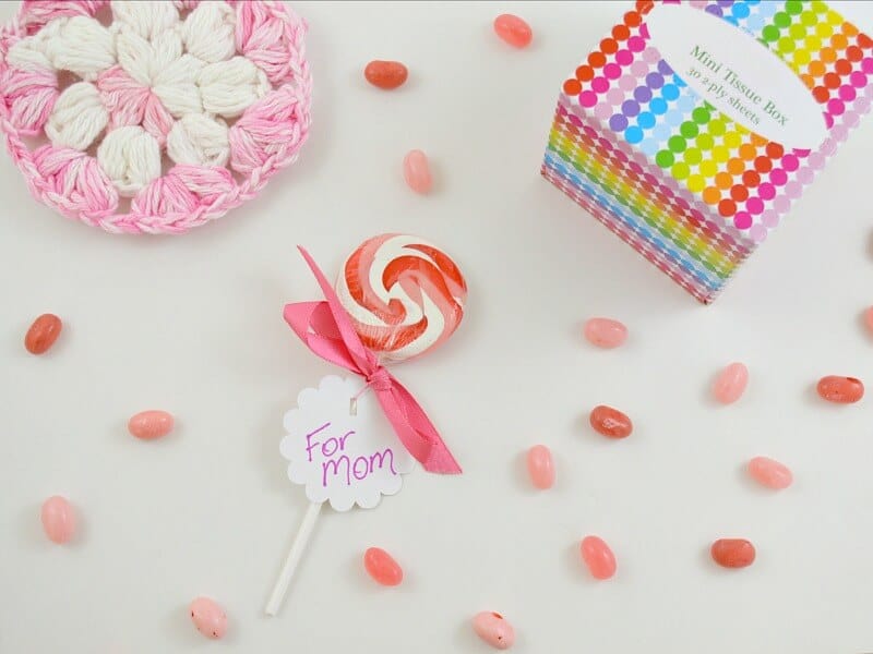 overhead view of pink candy, pink bath sponge and rainbow colored box of tissues on white table