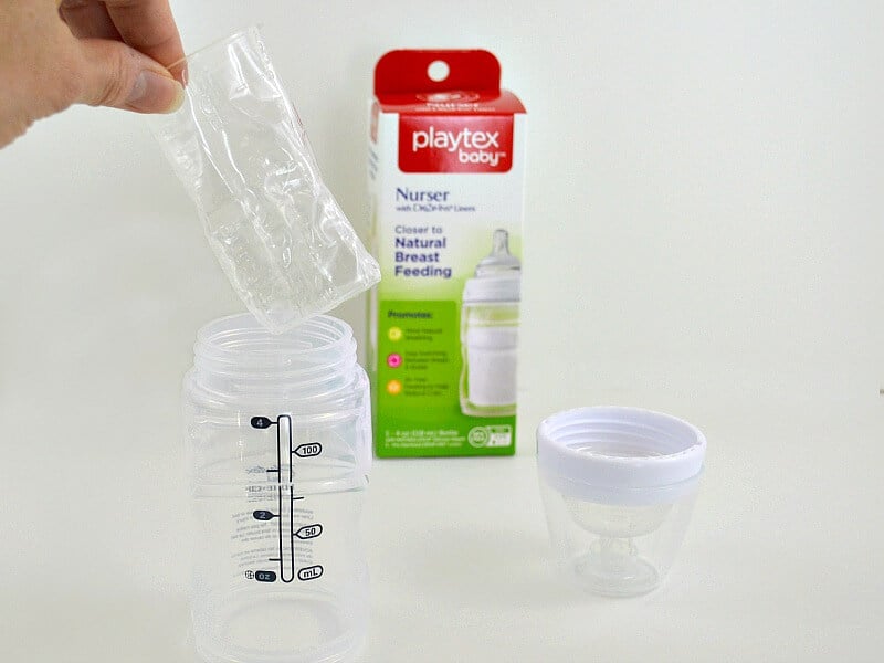 hand dropping formula bag into baby bottle with lid and product box nearby