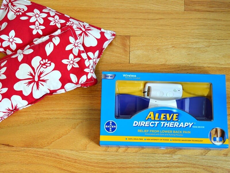 red floral heat packs next to box of back pain device on wood floor