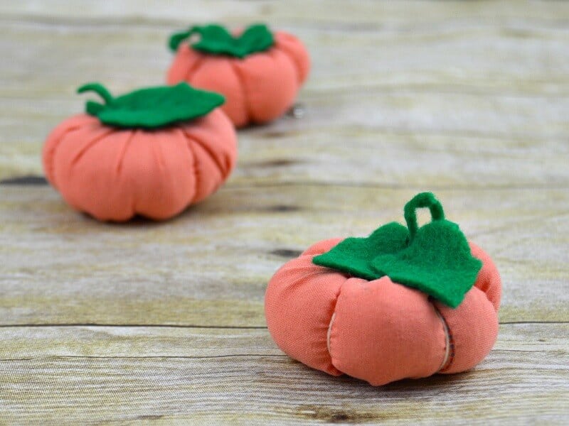 3 orange and green fabric pumpkins on wood table