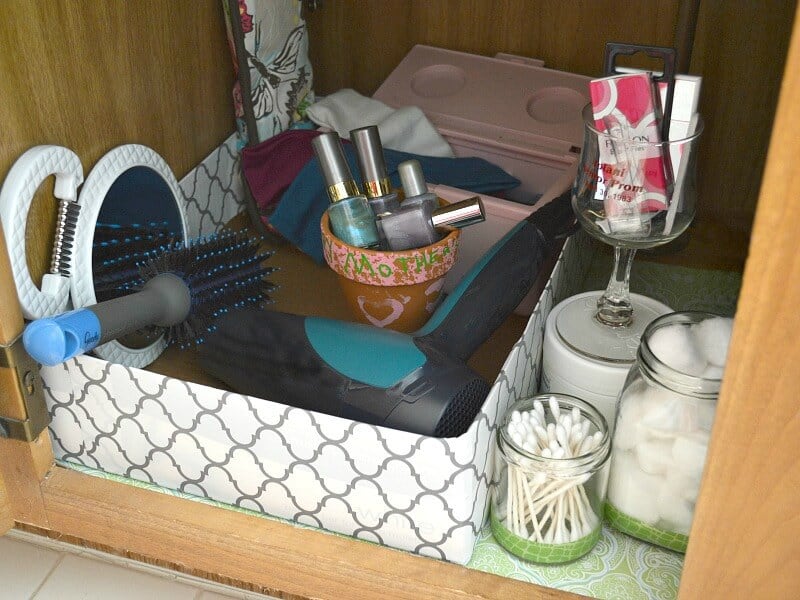 items neatly organized in cardboard box under bathroom sink