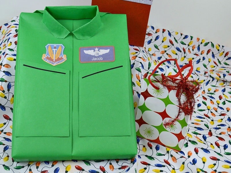 wrapped presented decorated to look like a green Air Force flight suit sitting on wrapping paper.