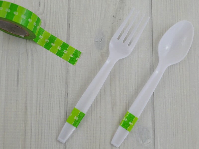 roll of green washi tape that looks like a football field next to fork and spoon decorated with the washi tape