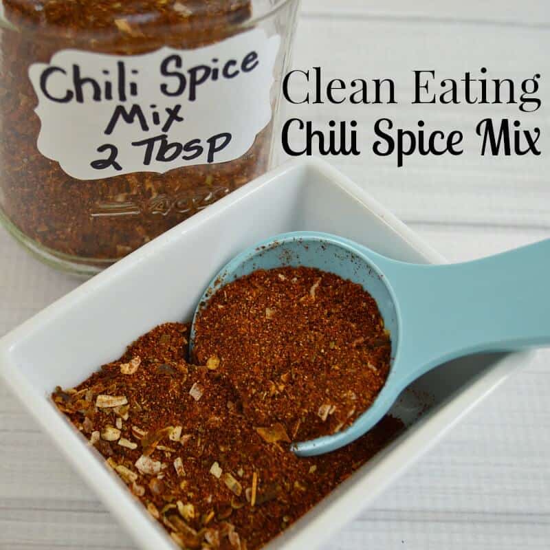 jar of chili spice mix with bowl of spice and measuring spoon in the foreground