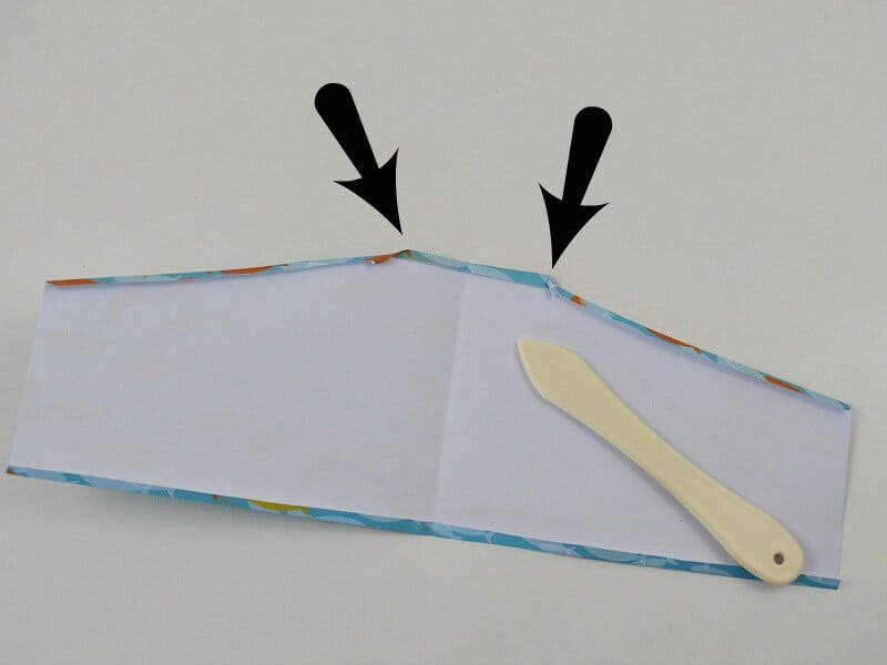 paper with edges folded over and bone folder tool 