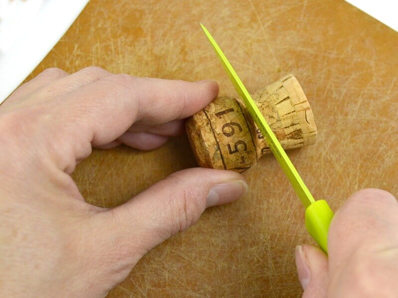 hands cutting end off champagne cork with green knife