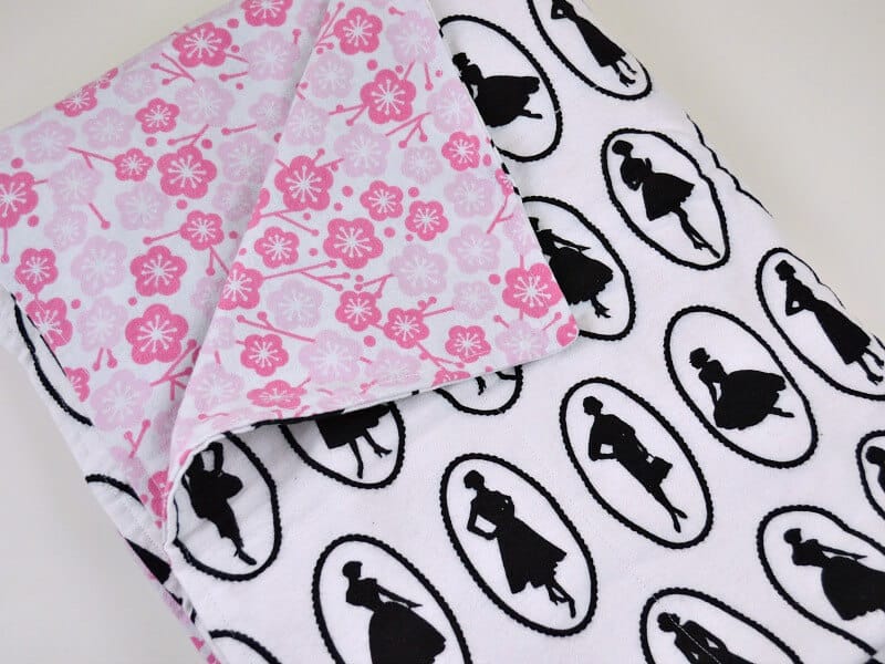 flannel blanket with black and white pattern on one side and pink flowers on the other side