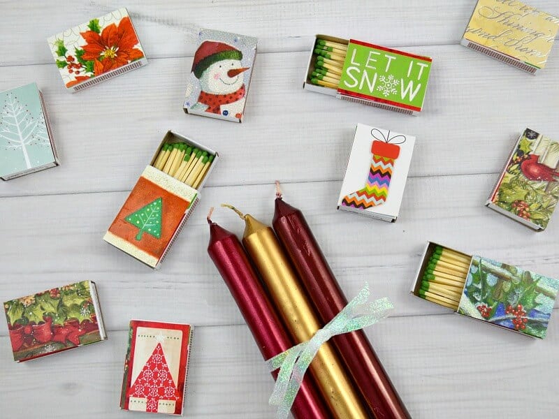 set of red and gold candles and various matchboxes covered in Christmas paper.