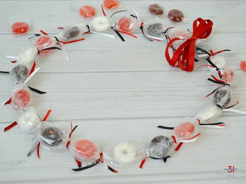 Angle view of candy lei with red, white and black ribbon.