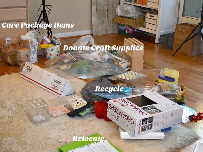 piles of items on rug in a craft room with text reading Care Package Items, Donate Craft Supplies, Recycle, Relocate