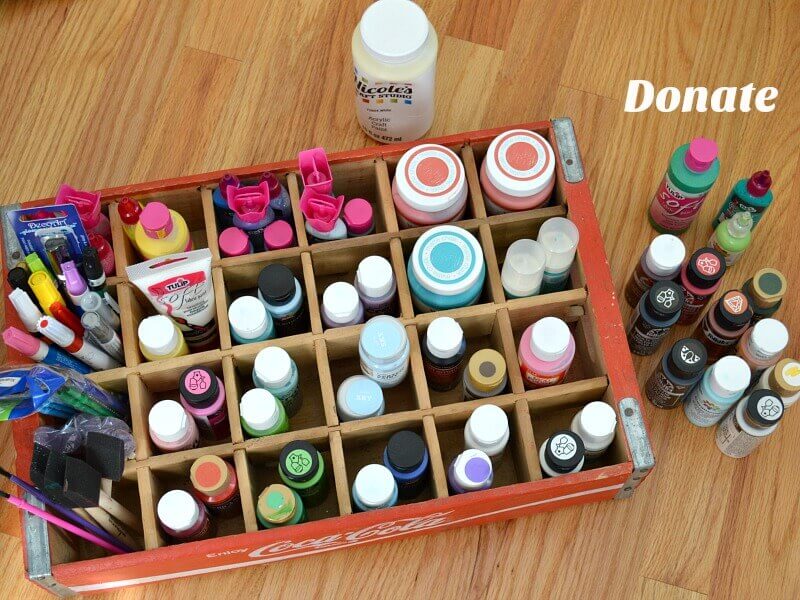 overhead view of craft paints in crate and some sitting next to crate with text reading Donate