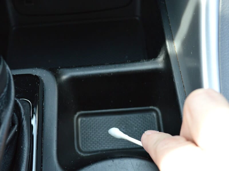 hand cleaning car console with cotton swab