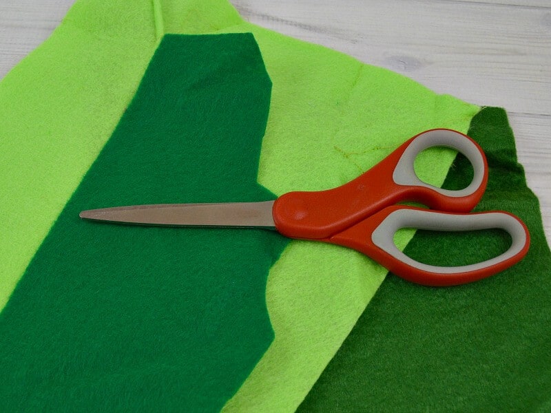 stack of green and light green felt squares with red pair of scissors