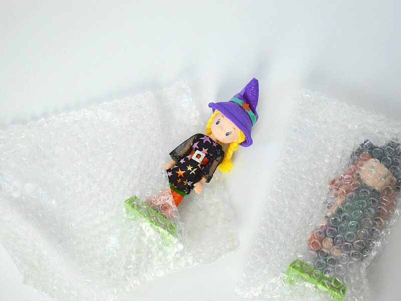 2 cute witch figurines, one in bubble wrap bag and one halfway in bubble wrap bag