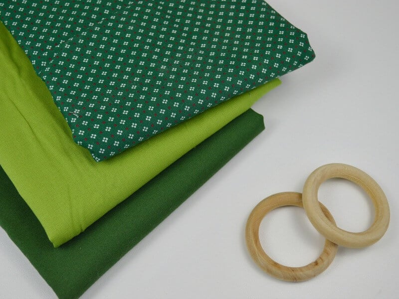 Stack of green fabric and 2 wood rings on white table