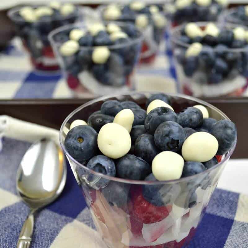 red, white, and blue fruit dessert cups with blue tablecloth and metal spoon