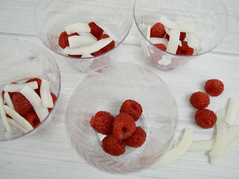 overhead view of clear cups with raspberries and coconut in cups