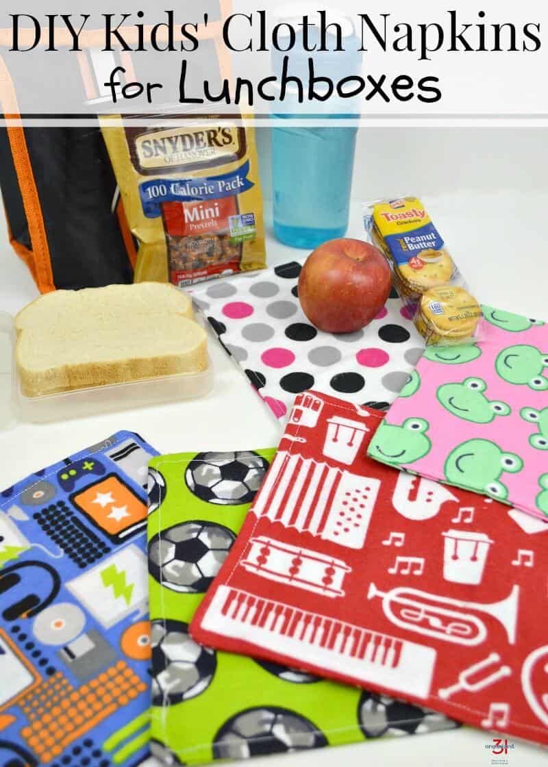 stack of colorful cloth napkins in foreground and lunch box with contents on table with title text reading DIY Kids' Cloth Napkins for Lunchboxes