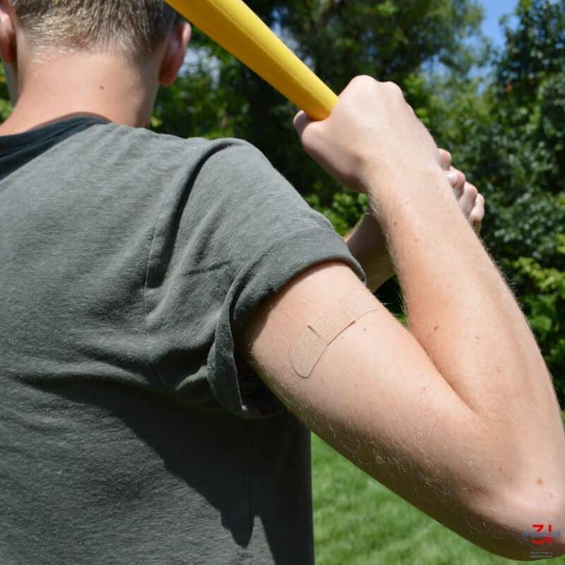 teen boy holding baseball bat and bandage on upper arm