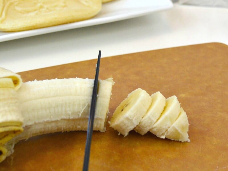 knife cutting banana on cutting board