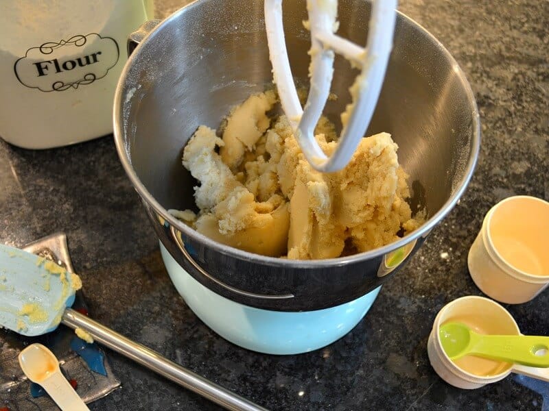 dough inside mixing bowl with measuring cups and spoons scattered around on counter