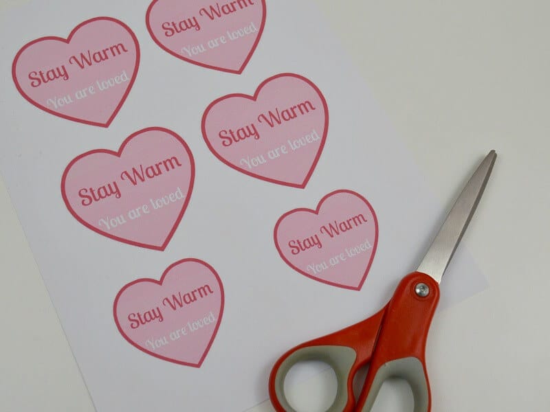 paper with pink hearts that say "Stay warm" and red scissors