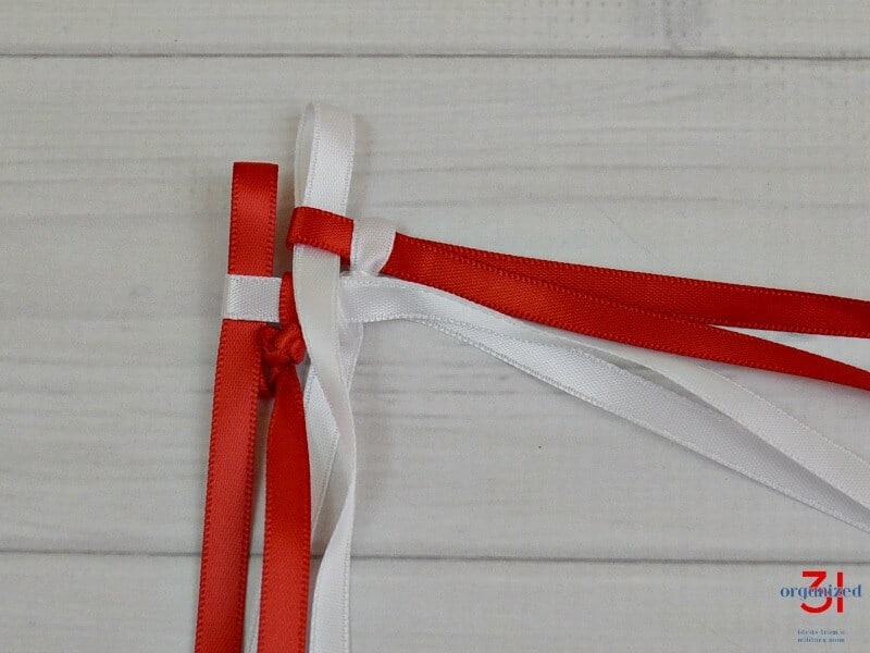 Start of ribbon lei with one red loop and one white loop.
